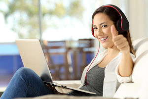 Studierende hört Musik und hat Laptop auf dem Schoß